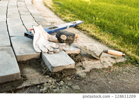 Laying paving stones on cement mortar. Laying a garden path made of tiles. Self-laying of concrete paving slabs in the courtyard of the house. do it yourself. DIY 128611209