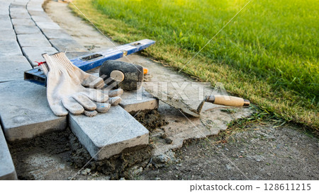 Laying paving stones on cement mortar. Laying a garden path made of tiles. Self-laying of concrete paving slabs in the courtyard of the house. do it yourself. DIY 128611215