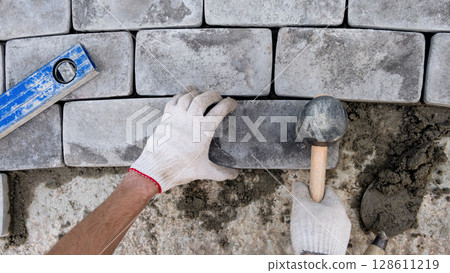 Laying paving stones on cement mortar. Laying a garden path made of tiles. Self-laying of concrete paving slabs in the courtyard of the house. do it yourself. DIY 128611219