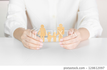 Hands Holding Paper Cutout Family Symbolizing Parental Care, Family Unity and Protection Hands Holding Paper Cutout Family Symbolizing Parental Care, Family Unity and Protection 128612097