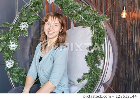 Smiling caucasian female adult in holiday decorated chair Smiling caucasian female adult in holiday decorated chair 128612144