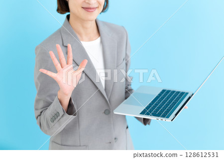 A middle-aged female business woman holding a laptop computer and showing five fingers 128612531