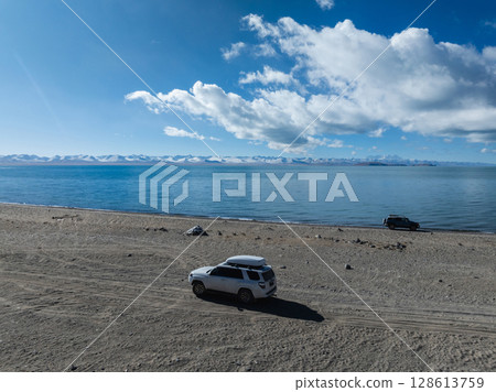Aerial view of offroad car running on high elevation lakeside Aerial view of offroad car running on high elevation lakeside 128613759