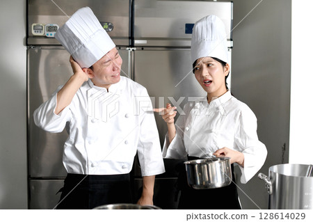 A male chef being scolded by a female chef in the kitchen A male chef being scolded by a female chef in the kitchen 128614029