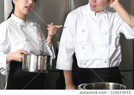 A male chef being scolded by a female chef in the kitchen A male chef being scolded by a female chef in the kitchen 128614033
