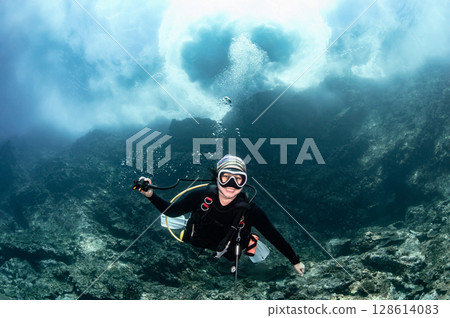 Asian female scuba diver looking at camera posing with the stunning wave breaking exploding above 128614083