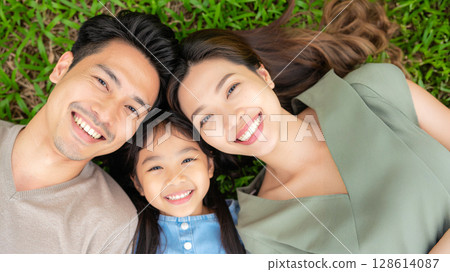 微笑的父母和孩子躺在草地上 128614087