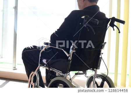 Rear view of an elderly man sitting in a wheelchair Rear view of an elderly man sitting in a wheelchair 128614456