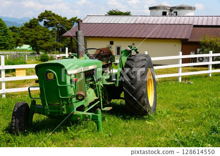 牧場上的舊破拖拉機和白色籬笆 牧場上的舊破拖拉機和白色籬笆 128614550