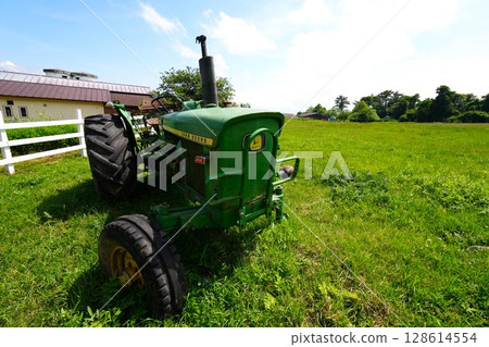 Old broken tractor and white fence on a ranch 128614554