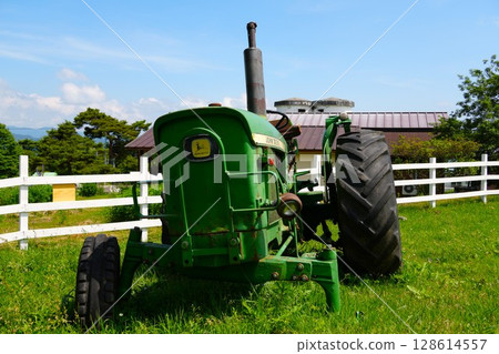 Old broken tractor and white fence on a ranch Old broken tractor and white fence on a ranch 128614557