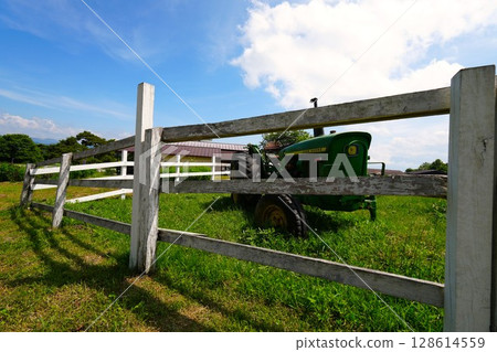 Old broken tractor and white fence on a ranch 128614559