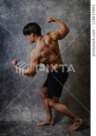 A man showing off his muscular body by doing the Arnold pose 128614862