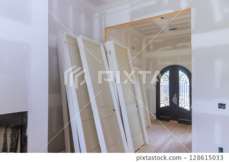 Interior construction several stacked doors against distinctive entry door in home under renovation. 128615033