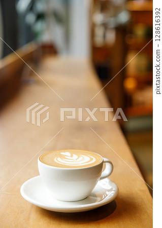 Cup of hot milk latte coffee on table by the window. Cup of hot milk latte coffee on table by the window. 128616392