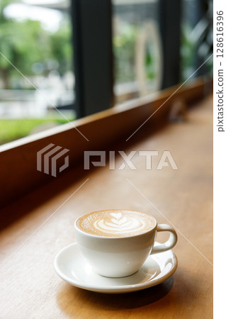 Cup of hot milk latte coffee on table by the window. Cup of hot milk latte coffee on table by the window. 128616396