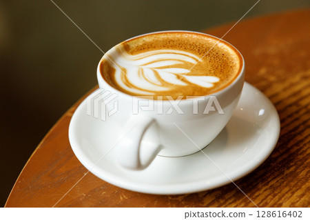 Cup of hot milk latte coffee on table by the window. 128616402