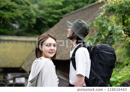 An inbound couple walking through a thatched-roofed village 128616483
