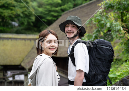 An inbound couple walking through a thatched-roofed village 128616484