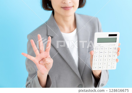 一位中年女商界女性拿著白色計算器,用四根手指指向上方 一位中年女商界女性拿著白色計算器,用四根手指指向上方 128616675