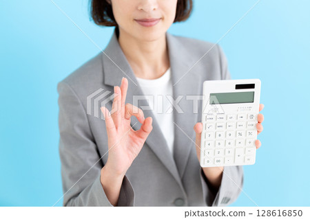 一位中年女商界女性手持白色計算器,做圓形標誌 一位中年女商界女性手持白色計算器,做圓形標誌 128616850