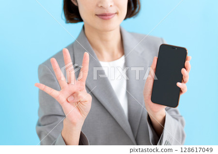 一位中年女商界女性手持智慧型手機，四根手指向上指 128617049
