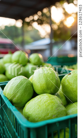 Fresh green guava fruit in plastic crate ready for export with processed agriculture products in market during sunset light 128617403