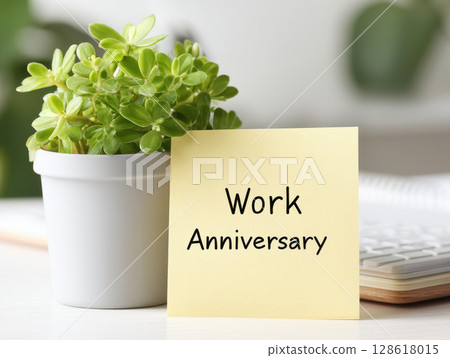 Happy work anniversary message is displayed on yellow sticky note next to green potted plant on desk, creating cheerful and positive office atmosphere Happy work anniversary message is displayed on yellow sticky note next to green potted plant on desk, creating cheerful and positive office atmosphere 128618015