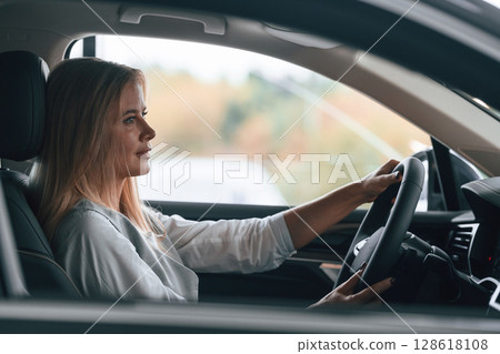 Woman is sitting in a car and driving it Woman is sitting in a car and driving it 128618108