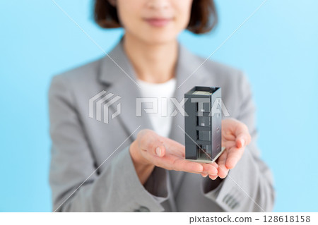 Middle-aged female business woman holding a model of an office building Middle-aged female business woman holding a model of an office building 128618158