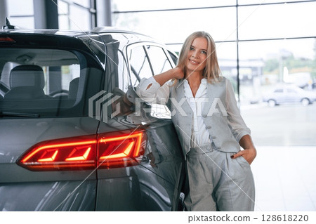 Woman in formal clothes is in the car dealership 128618220