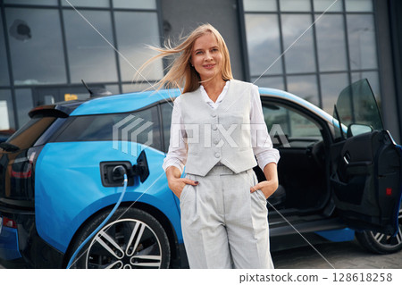 Standing and posing. Woman on the electric cars charge station at daytime 128618258