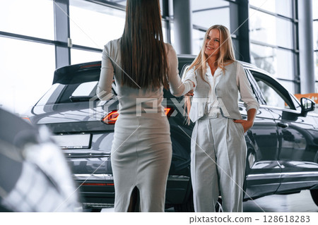 Handshake, greetings gesture. Female manager is helping woman customer in the car dealership salon Handshake, greetings gesture. Female manager is helping woman customer in the car dealership salon 128618283