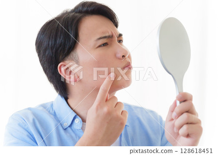 A man looking in the mirror and doing skin care A man looking in the mirror and doing skin care 128618451