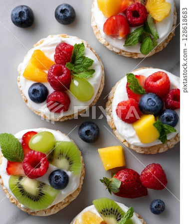 Colorful assorted fruit tarts with berries, kiwi, pineapple, and mint on rice cakes. Colorful assorted fruit tarts with berries, kiwi, pineapple, and mint on rice cakes. 128618683