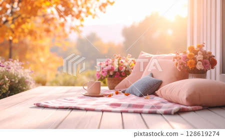 Hot drink and picnic blanket surrounded by autumn leaves and flowers 128619274