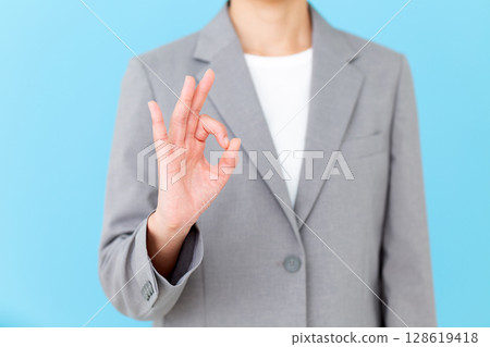 A middle-aged female business woman wearing a gray suit making a circle sign 128619418