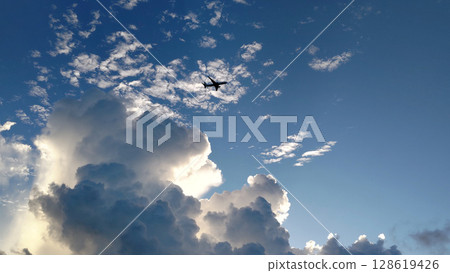 夕陽照射下的雲朵和飛機 128619426