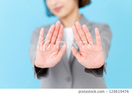 A middle-aged business woman in a suit refusing with both hands 128619476