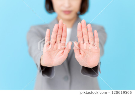 A middle-aged business woman in a suit refusing with both hands 128619566