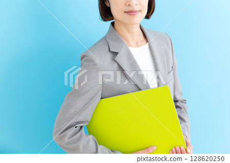A middle-aged business woman wearing a gray suit and holding a file 128620250