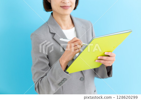 A middle-aged business woman wearing a gray suit and holding a file 128620299