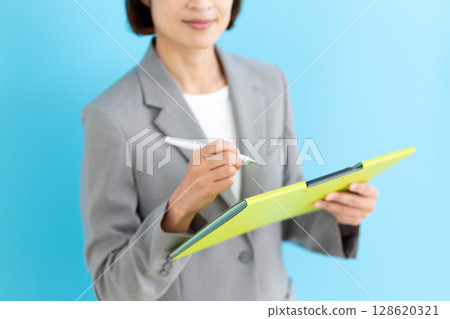 一位身穿灰色西裝、手拿文件的中年女商人 128620321