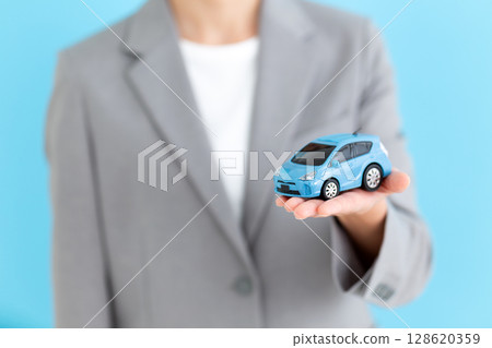 Middle-aged female business woman holding a model of a car 128620359