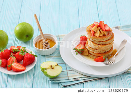 pancakes topped with apple slices and strawberries 128620579