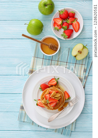 pancakes topped with apple slices and strawberries pancakes topped with apple slices and strawberries 128620581