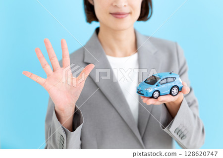 一位中年女商界女性手拿模型車，伸出五根手指 128620747