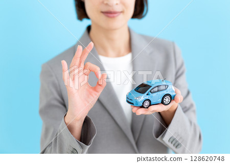 一位中年女商界女性手持汽車模型，做著圓圈手勢 128620748