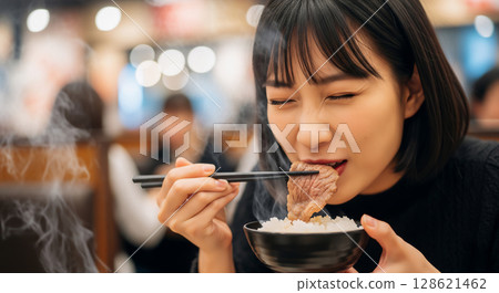 A woman eating grilled meat and rice 128621462