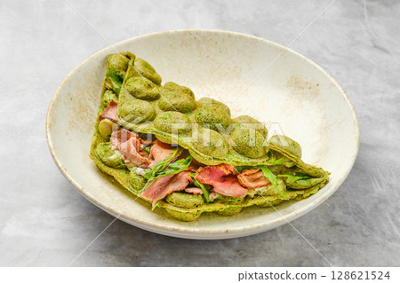 Delicious matcha pancake filled with savory ingredients served in a rustic bowl Delicious matcha pancake filled with savory ingredients served in a rustic bowl 128621524
